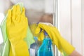 Woman hands in protective gloves cleaning window with rag and cleanser spray at home Royalty Free Stock Photo