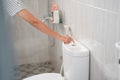 woman hands push a flush button on the toilet