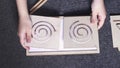 Woman hands put white sheet of paper in two-sided wooden stencil labyrinth and place stencils on top