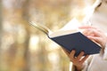 Woman hands reading a book in autumn in a park