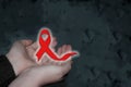 Woman hands with red gloving ribbon on smoke gray background , world aids day