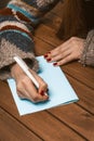 Woman Hands with Red Manicure on a Wooden Table Write a Greeting Card with a Pen. Woman Fill in a Letter on a Piece of Royalty Free Stock Photo