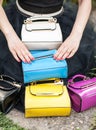 Woman hands resting on colored bags. Many colorful purses