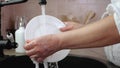 Woman hands rinse plate at the kitchen sink - slow motion