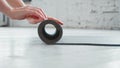 Woman hands roll grey rubber mat to train on parquet floor in spacious light yoga studio