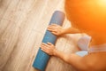 Woman hands rolled up yoga mat on gym floor in yoga fitness training room. Home workout woman close up hands rolling