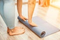 Woman hands rolled up yoga mat on gym floor in yoga fitness training room. Home workout woman close up hands rolling