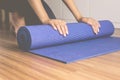 Woman hand rolling or folding blue yoga mat after a workout,Exercise equipment Healthy fitness and sport concept Royalty Free Stock Photo