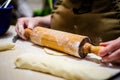 Woman hands rolling out dough in flour with rolling pin in her home kitchen. Selective focus Royalty Free Stock Photo