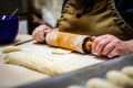 Woman hands rolling out dough in flour with rolling pin in her home kitchen. Selective focus Royalty Free Stock Photo