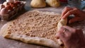 Woman hands rolling up the dough for a wallnut roll cake