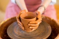 Hands sculpts cup from clay pot. Workshop of modeling on potter wheel Royalty Free Stock Photo