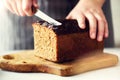 Woman hands slicing freshly backed bread. Handmade brown loaf of bread, bakery concept, homemade food, healthy eating Royalty Free Stock Photo