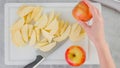 Woman hands slicing red apples on a white cutting board on the kitchen table, view from above, apple cake recipe Royalty Free Stock Photo