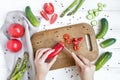 Woman hands slicing sweet pepper on wooden cutting board, surrounded by vegetables. Flat lay, top view Royalty Free Stock Photo