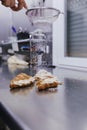 Woman hands sprinkling white flour over croissants on bakery Royalty Free Stock Photo