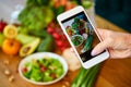 Woman hands take smartphone food photo of vegetables salad with tomatoes and fruits. Phone photography for social media or Royalty Free Stock Photo