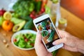 Woman hands take smartphone food photo of vegetables salad with tomatoes and fruits. Phone photography for social media or Royalty Free Stock Photo