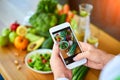 Woman hands take smartphone food photo of vegetables salad with tomatoes and fruits. Phone photography for social media or Royalty Free Stock Photo