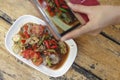 Woman hands takes photo of local Thai food on table with smartphone Royalty Free Stock Photo