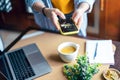 Woman hands taking photo of coffee cup, green leaves and breakfast at home in brown kitchen at smartphone. Top view Royalty Free Stock Photo