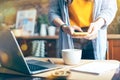 Woman hands taking photo of coffee cup, green leaves and breakfast at home in brown kitchen at smartphone. Top view Royalty Free Stock Photo