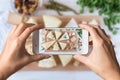 Woman hands taking a photo of different kinds of delicious cheese with nuts