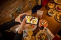 Woman hands taking picture, with smartphone, of the food served in the restaurant Royalty Free Stock Photo