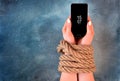 Woman hands tied with rope on a concrete background suggesting internet or social media addiction or captivity.
