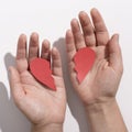 Woman hands with two halves of red paper heart over white Royalty Free Stock Photo