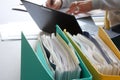 Woman hands typing on laptop computer with binders filled with papers  in foreground. Selective focus Royalty Free Stock Photo