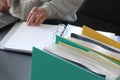 Woman hands typing on laptop computer with binders  filled with papers in foreground. Selective focus Royalty Free Stock Photo