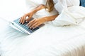 Woman hands typing on laptop keyboard in bedroom at home