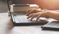 Woman hands typing on laptop keyboard with books and various devices on wooden table in home office room Royalty Free Stock Photo