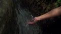 Woman hands under the water of a waterfall in the mountains. female hand gathering fresh clean source water, close up,