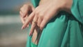 Woman hands untie the laces on turquoise cape and expose the belly close up. Dress fluttering in the wind