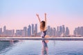 Woman with hands up enjoying morning view from roof top infinity pool at asia Royalty Free Stock Photo