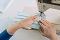 Woman hands using the sewing machine to sew the face home made diy medical mask during the coronavirus pandemia. Royalty Free Stock Photo