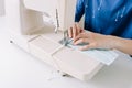 Woman hands using the sewing machine to sew the face home made diy medical mask during the coronavirus pandemia. Royalty Free Stock Photo