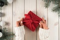 Woman hands in warm sweater tie bow on red furoshiki present box with spruce twigs, Christmas toy decoration. Top view Royalty Free Stock Photo