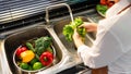 Woman hands washing Vegetables for Preparation of vegan salad on the worktop near to sink in a modern kitchen, Homemade healthy Royalty Free Stock Photo
