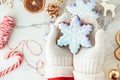 Woman hands wearing white mittens and holding snowflake shaped gingerbread cookie with festive icing on the decorated Christmas Royalty Free Stock Photo