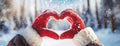 Woman hands in winter gloves showing heart symbol shaped on snow drifts forest background. Love on Valentines day Royalty Free Stock Photo