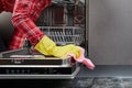 The woman hands in yellow gloves cleaning dishwasher panel with pink rag in kitchen.close up Royalty Free Stock Photo