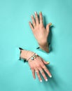 woman hands with yellow pink white pattern nail polish and silver stacking