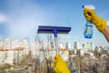 Woman hands with yellow rubber gloves holding window glass cleaning tool and spray bottle with detergent over window background Royalty Free Stock Photo