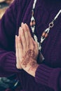 Woman hands in namaste mudra gesture with henna drowing on hands outdoor shot