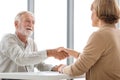 Woman handshaking greeting senior man client, Health visitor, and a senior man during a home visit Royalty Free Stock Photo