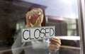 Woman hanging banner with closed word on door