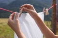 Woman hanging clean laundry with clothespin on washing line outdoors, closeup Royalty Free Stock Photo